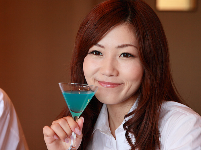 青いカクテルを飲んでいる女性